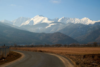 Road leading towards mountains against sky