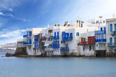 Buildings by sea against blue sky