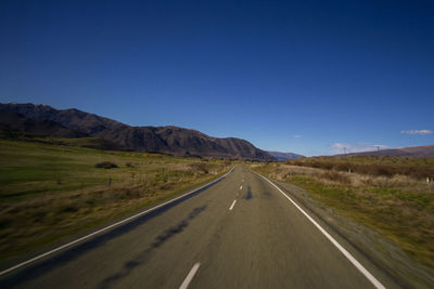 Road amidst landscape against clear blue sky