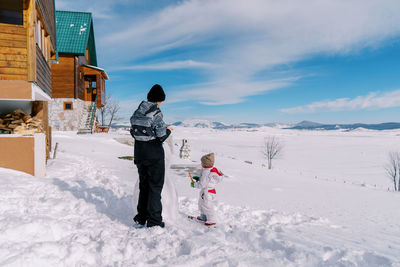 Rear view of woman standing on snow covered landscape