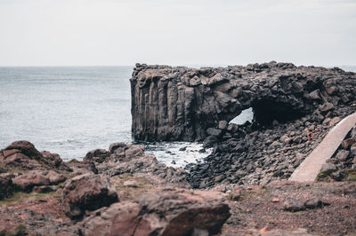 Rock formations by sea against clear sky