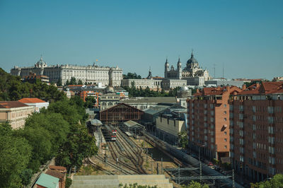 Royal palace and almudena cathedral on the horizon and a train station with rails in madrid, spain.