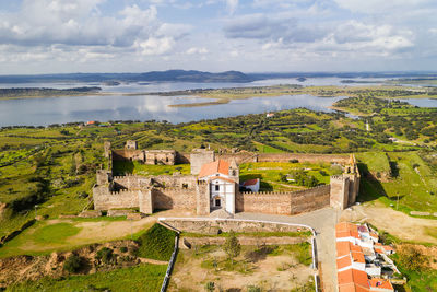 Mourao drone aerial view of castle with alqueva dam lake behind in alentejo, portugal
