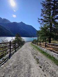 Footpath by lake against sky