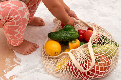 Cropped image of girl picking fruit from bag