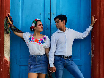 Young couple standing against blue wall