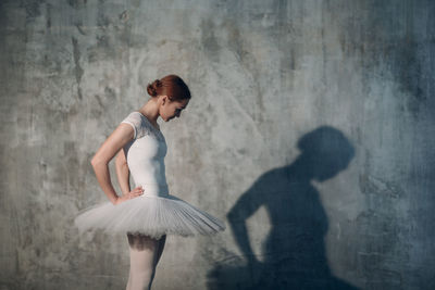 Woman dancing against gray wall