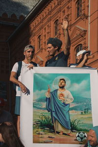 Young man with woman standing against built structure