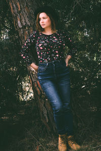 Portrait of young woman standing by tree