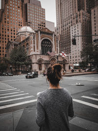 Rear view of woman on city street by buildings