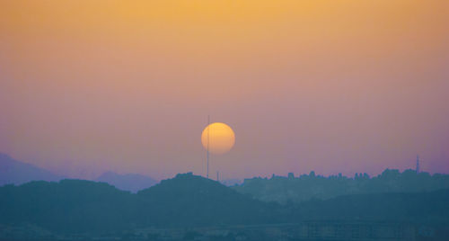 Scenic view of silhouette mountains against orange sky