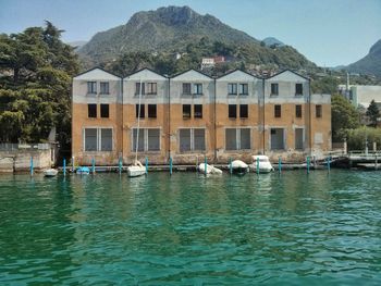 Sailboats in lake by buildings against sky