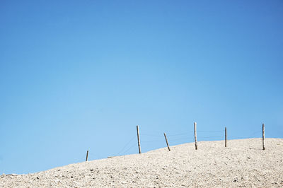 Scenic view of beach and posts against clear blue sky