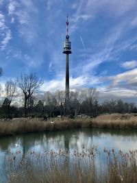 Reflection of tower in lake against cloudy sky