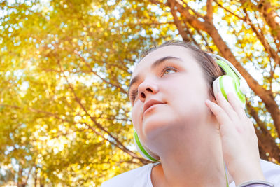Portrait of teenage girl looking away against trees