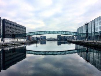 Reflection of modern buildings in city against sky