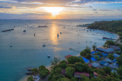 High angle view of sea and buildings against sky at sunset