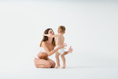 Side view of woman exercising against white background