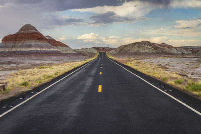 Road leading towards mountains against sky