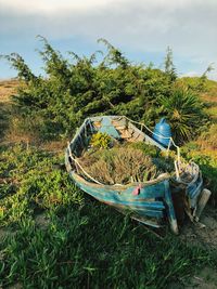 Abandoned boat moored on land against sky