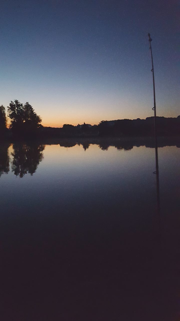 water, tranquility, tranquil scene, reflection, lake, scenics, tree, silhouette, beauty in nature, sunset, clear sky, nature, idyllic, copy space, sky, calm, standing water, blue, dusk, outdoors