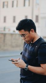 Young man using mobile phone while standing outdoors