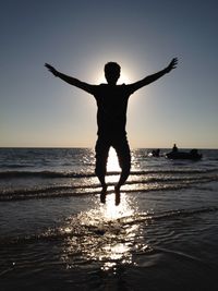 Man jumping in sea against sky