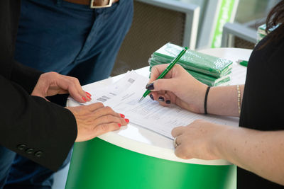 Midsection of colleagues filling form on table