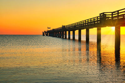 Pier over sea against sky during sunset