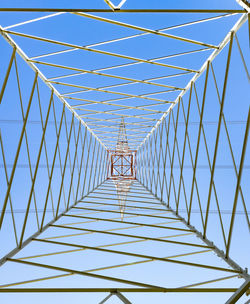 Electricity pylon in perspective seen from below with blue sky background