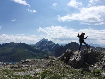 Girl balancing on rocks against sky