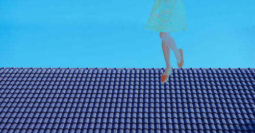 Low section of woman against blue sky
