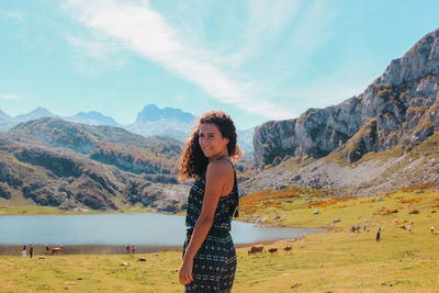 Portrait of young woman standing on mountain against sky