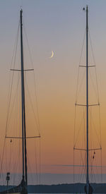 Silhouette of sailboat against sky during sunset with moon