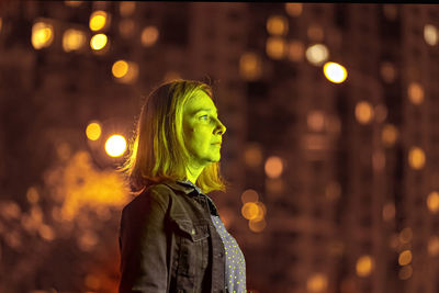 Portrait of a young woman in a night city in neon green on a summer evening. city lights.