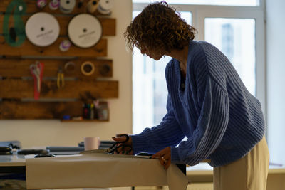 Seamstress draft paper patterns on textile with chalk and ruler. clothes designer work in studio