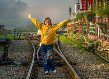 Rear view of woman standing on railroad track