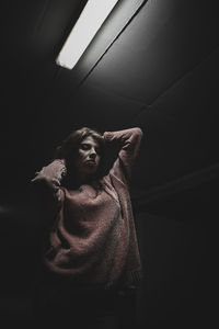 Low angle view of woman standing against dark background