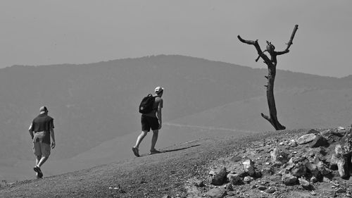 Rear view of men standing on mountain against sky