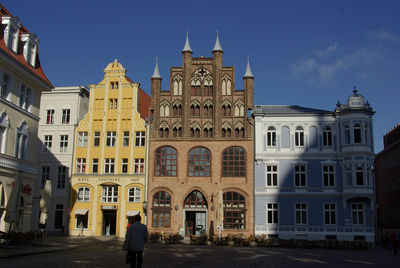 Rear view of man standing by historic buildings in city against sky