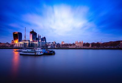 City by river and buildings against sky