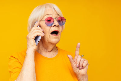 Portrait of young woman wearing mask against yellow background