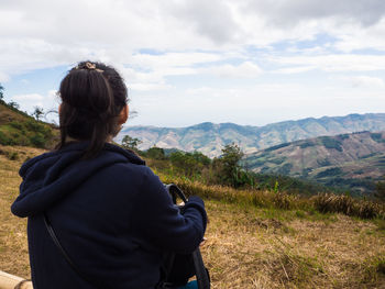 Rear view of woman on grass against mountains and sky