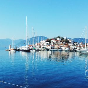 Boats sailing in harbor against clear blue sky