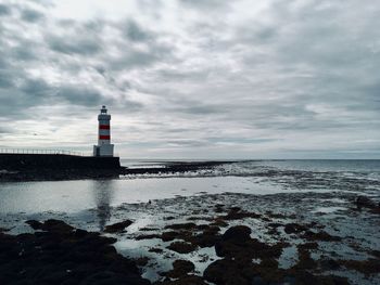 Lighthouse by sea against sky