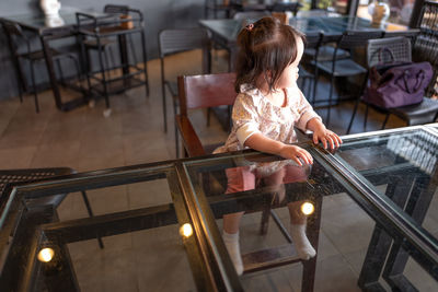 Thoughtful baby girl sitting on chair in restaurant