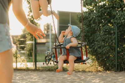 Low section of woman swinging at playground