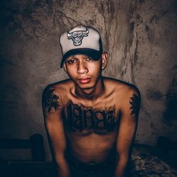 Portrait of shirtless man standing against wall