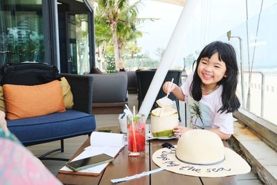 Portrait of happy girl sitting on table