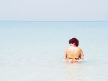 Rear view of shirtless man in sea against sky